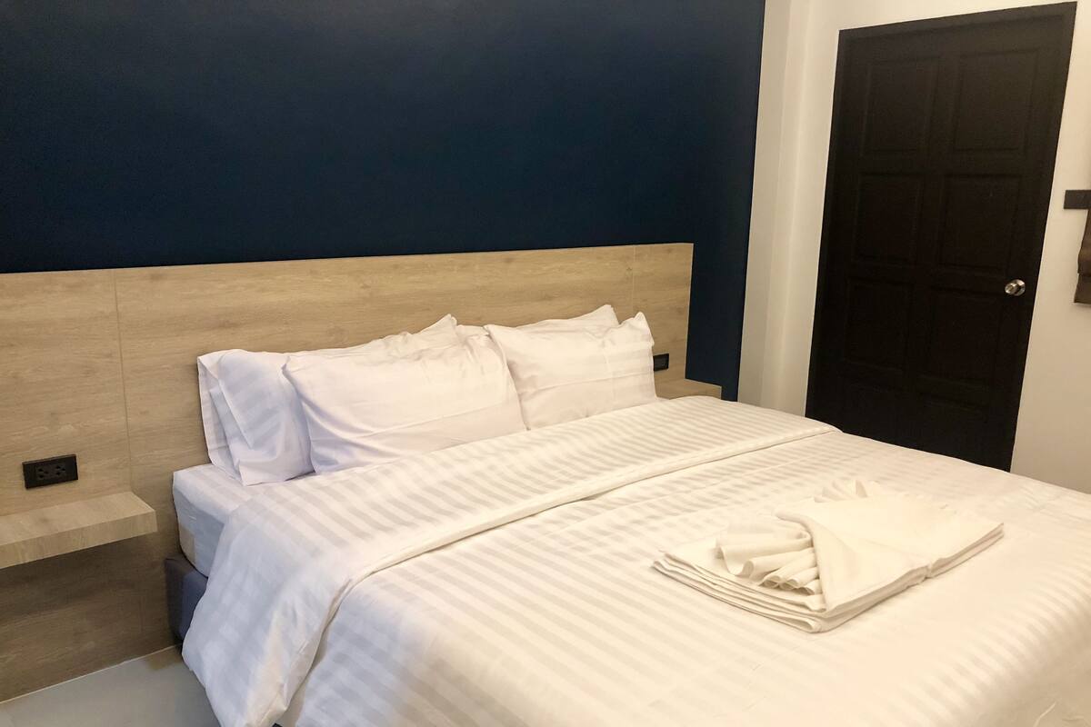 A neatly made bed with white linens and a folded towel on the bed.