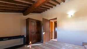 A bedroom with a bed, wooden wardrobe, and a bench. - Al Castelluccio (Monteverdi Marittimo)