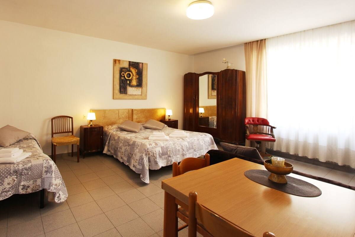 Ein Hotelzimmer mit zwei Einzelbetten, einem Holztisch, einem roten Stuhl und einem großen Spiegel.