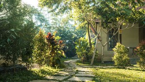 A stone pathway leading to a building surrounded by lush greenery and trees. - Relax & rejuvinate at Muda Living, only minutes from Ubud Market! (Ubud)