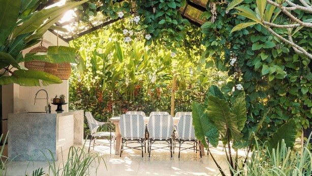 A wooden pathway leading to a seating area with chairs under a lush green archway. - Relax & rejuvinate at Muda Living, only minutes from Ubud Market! (Ubud)