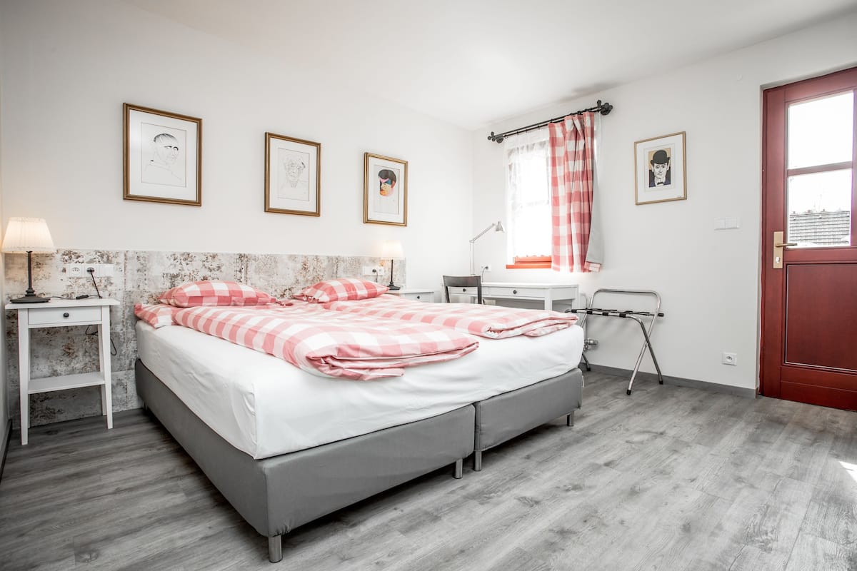 A bedroom with a bed, bedside tables, a desk, a chair, and a window with curtains.