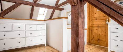 A room with wooden beams, white cabinets, and a wooden door.