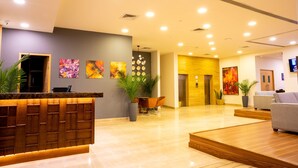 Un moderno vestíbulo de hotel con mostrador de recepción, zona de estar y obras de arte en las paredes.