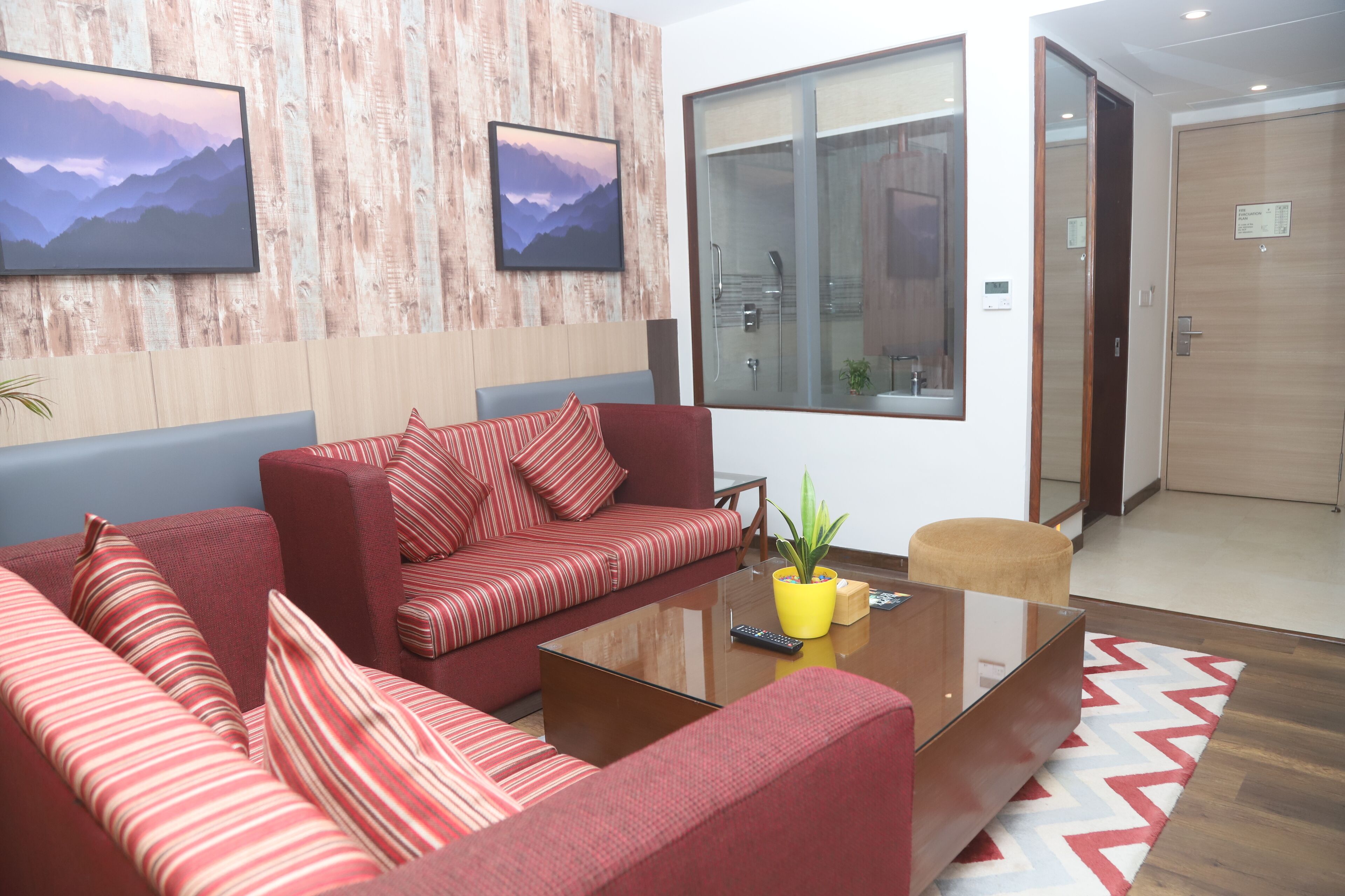 A modern living room with red sofas, a glass coffee table, and a large window with a view of a mountain.