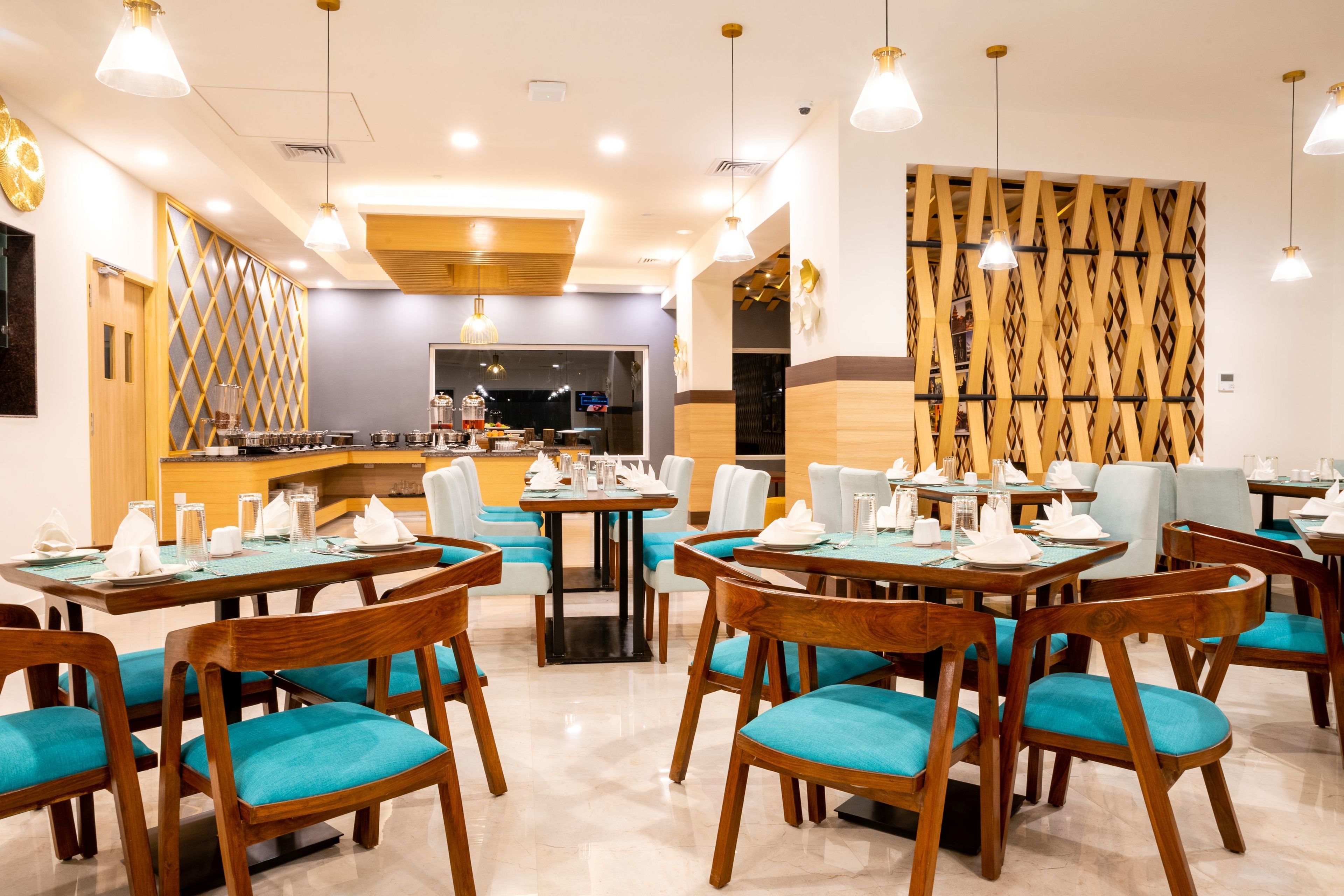 Restaurante com mesas e cadeiras de madeira, um espaço de bar e uma parede decorativa.