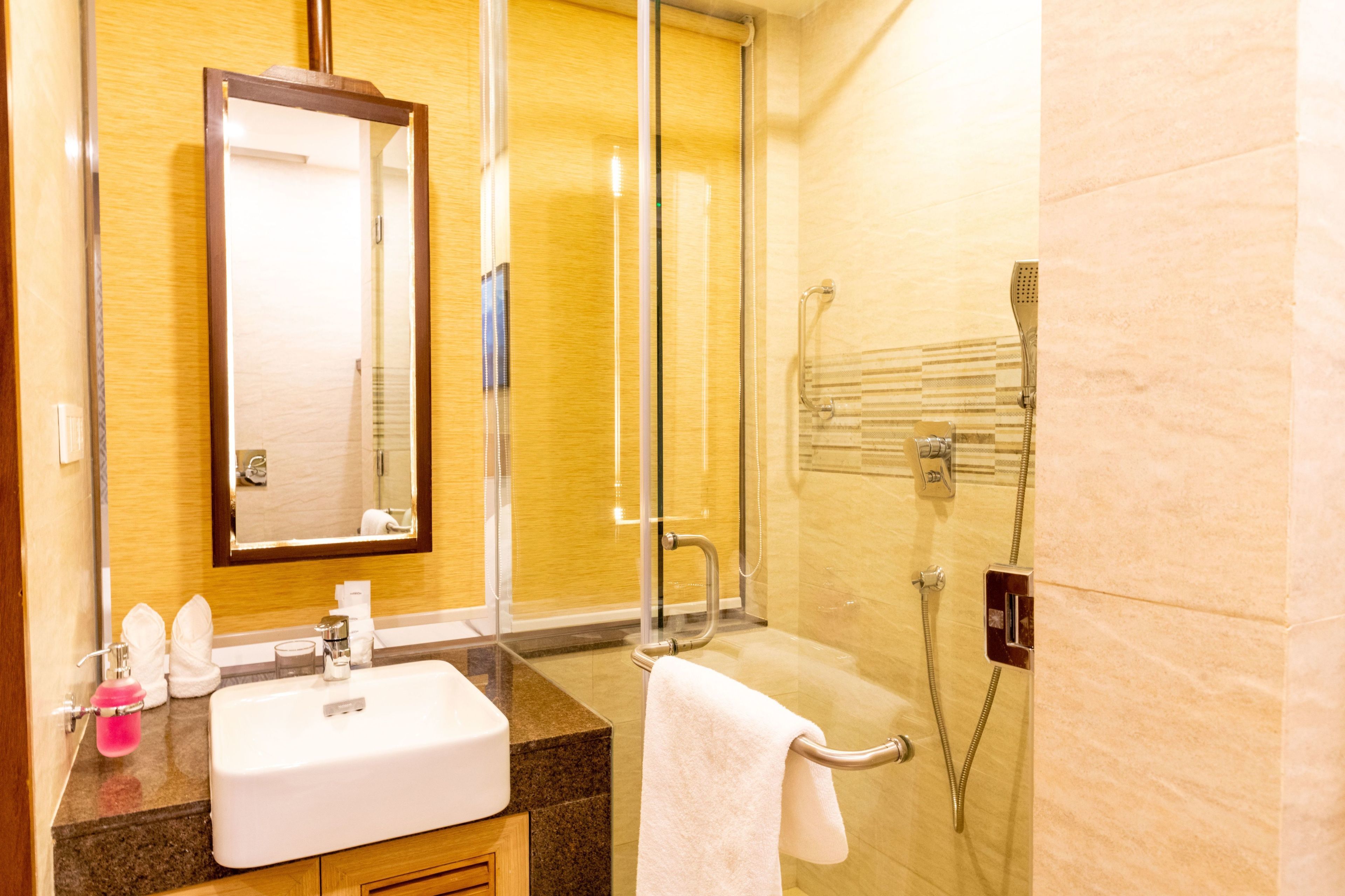 A bathroom with a sink, mirror, towel rack, and shower.