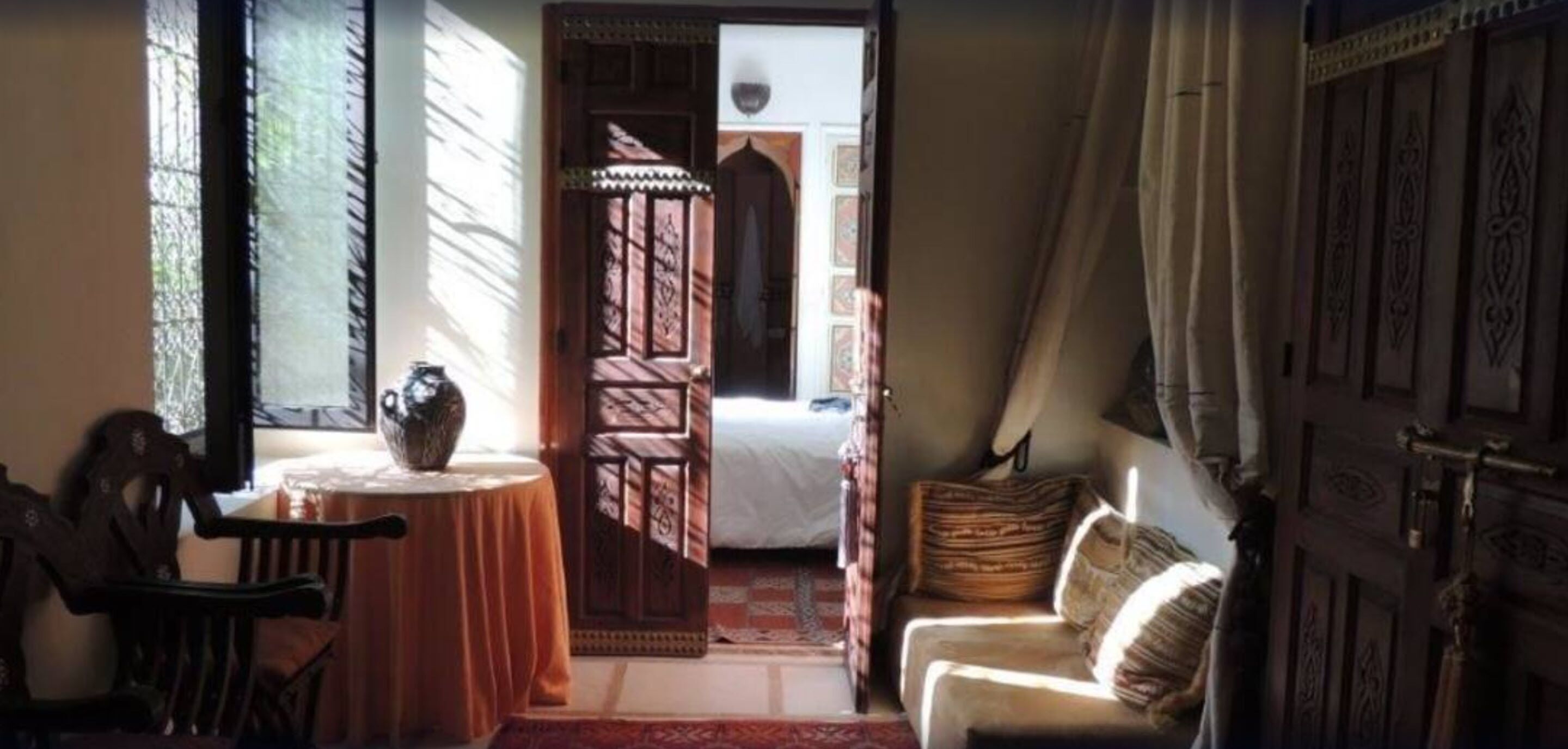 Una habitación con una cama, una silla, una mesa y una puerta que da a otra habitación.