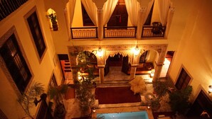 A traditional courtyard with a central seating area, ornate arches, and potted plants. - Riad Al Loune (Marrakech)