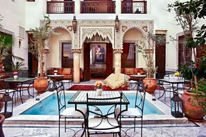 A courtyard with a pool, outdoor seating, and decorative arches. - Riad Al Loune (Marrakech)