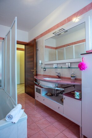 A bathroom with a glass shower enclosure, a sink with a pink towel, and a mirror above the sink. - Promenade (Jesolo)
