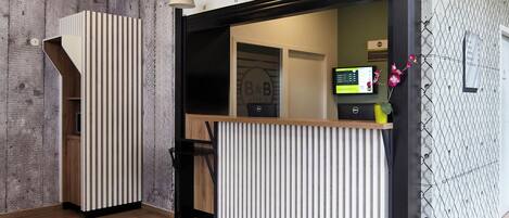 A reception area with a wooden desk, a patterned rug, and a reception desk with a vertical slat design.