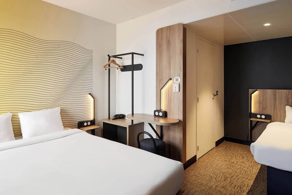Ein Hotelzimmer mit einem großen Bett, einem Schreibtisch mit Stuhl, einem Kleiderständer und einem Kleiderschrank.