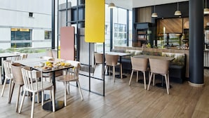 Un comedor moderno con mesas, sillas y una barra, con amplias ventanas.