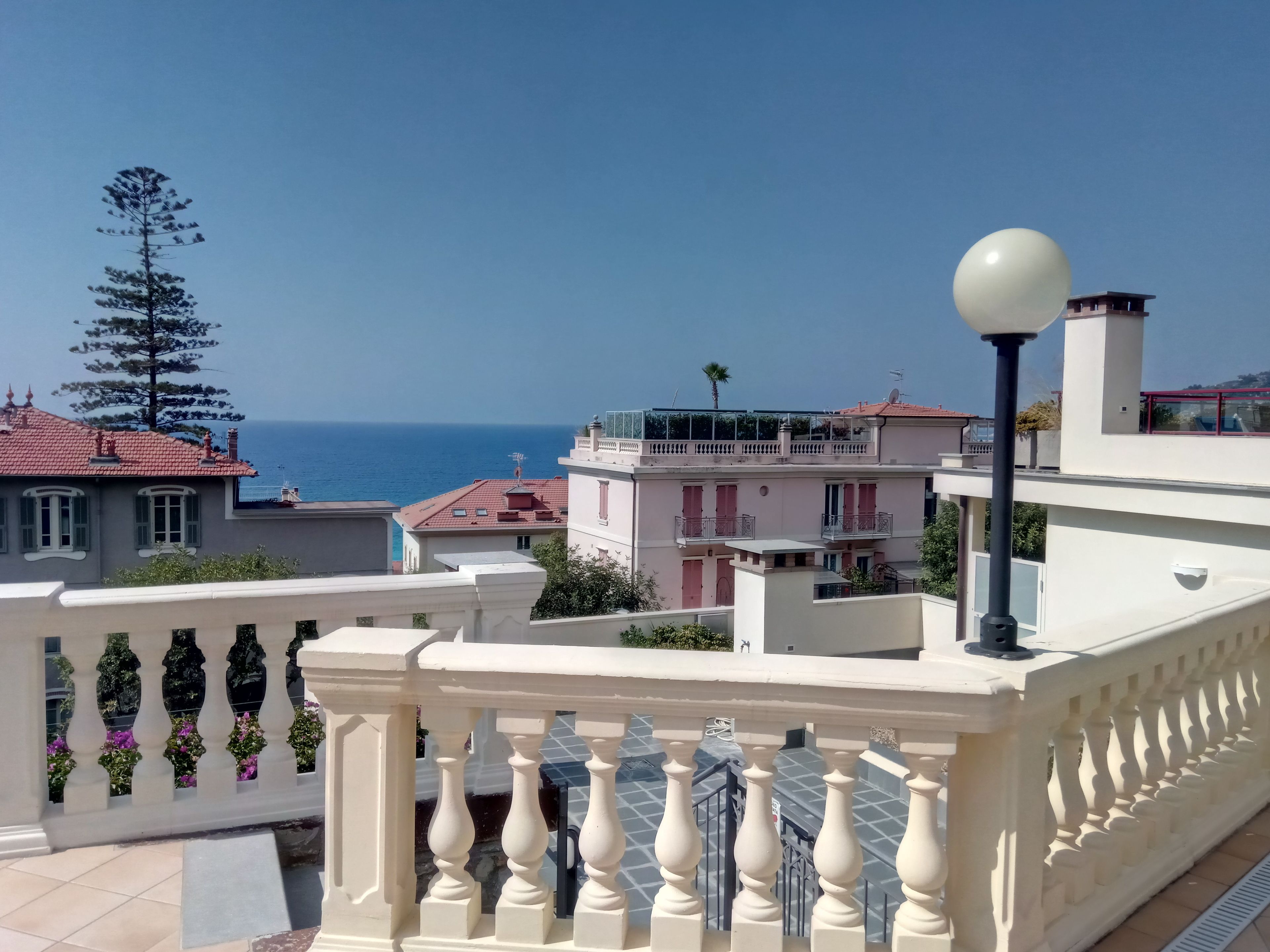 A coastal residential area with a balcony featuring a balustrade and a street lamp.
