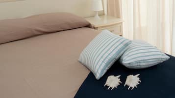 Una camera da letto con un letto, cuscini, un comodino, una lampada, un quadro e una finestra con tende.