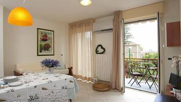 A dining area with a table set for four, a sofa, and a view of the outside balcony.