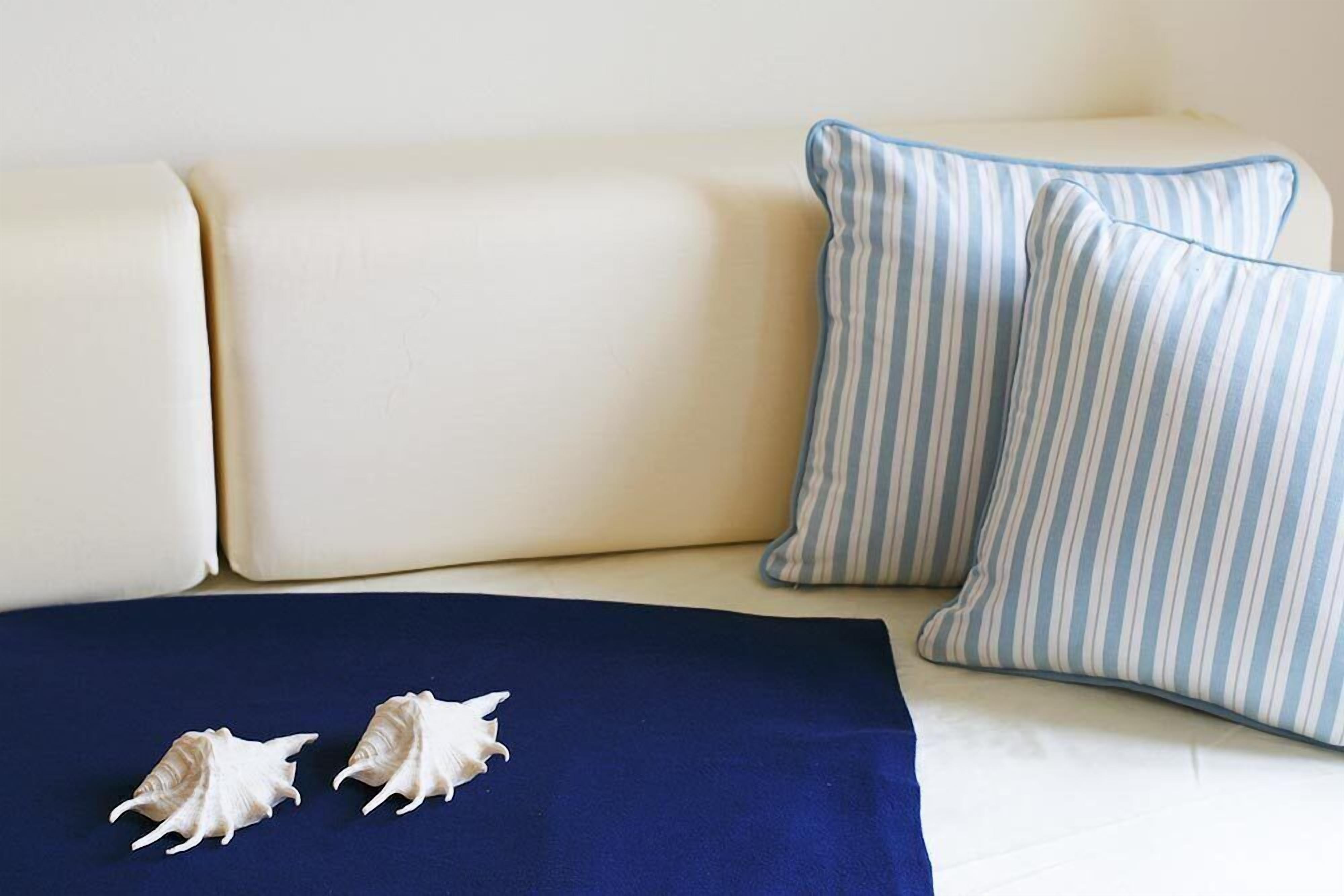 Ein beiges Sofa mit zwei gestreiften Kissen und einer dunkelblauen Decke.