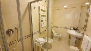 Un bagno con doccia vetro, wc, lavandino e specchio.