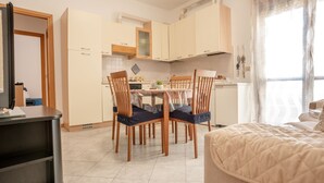 A modern kitchen with white cabinets, a dining table with chairs, and a large window with curtains. - Residence Cava Zuccherina (Jesolo)