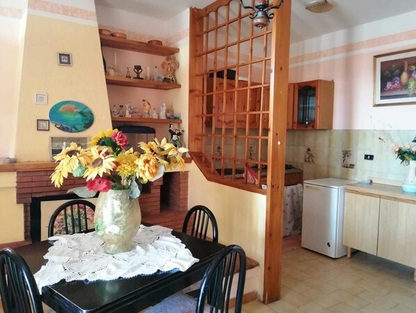 Un comedor con una mesa dispuesta para dos personas, un florero y un separador de madera.