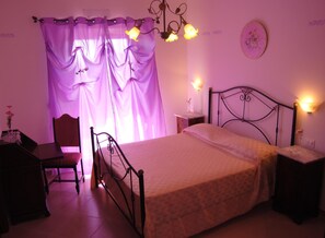 Un dormitorio con cama, una silla, un escritorio y una mesita de noche.