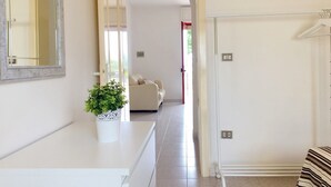 A hallway with a white sofa, a potted plant, and a mirror. - Villetta Gardenia (Morciano di Leuca)
