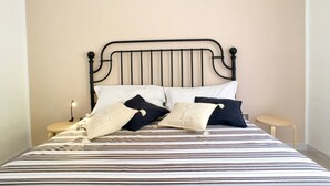 A bed with a striped bedspread, a black metal headboard, and two bedside tables with lamps. - Villetta Gardenia (Morciano di Leuca)