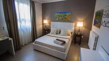 Habitación de hotel con cama, dos lámparas de noche, un cuadro en la pared y un radiador.