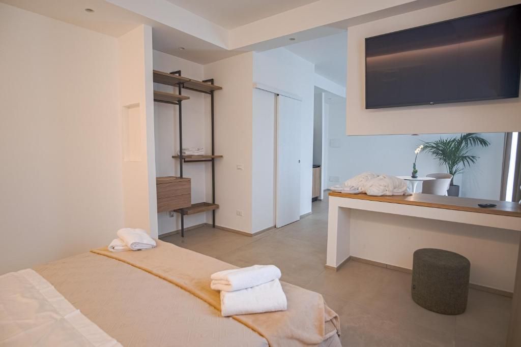 A modern hotel room with a bed, a desk, a television, and a bathroom visible through an open door.