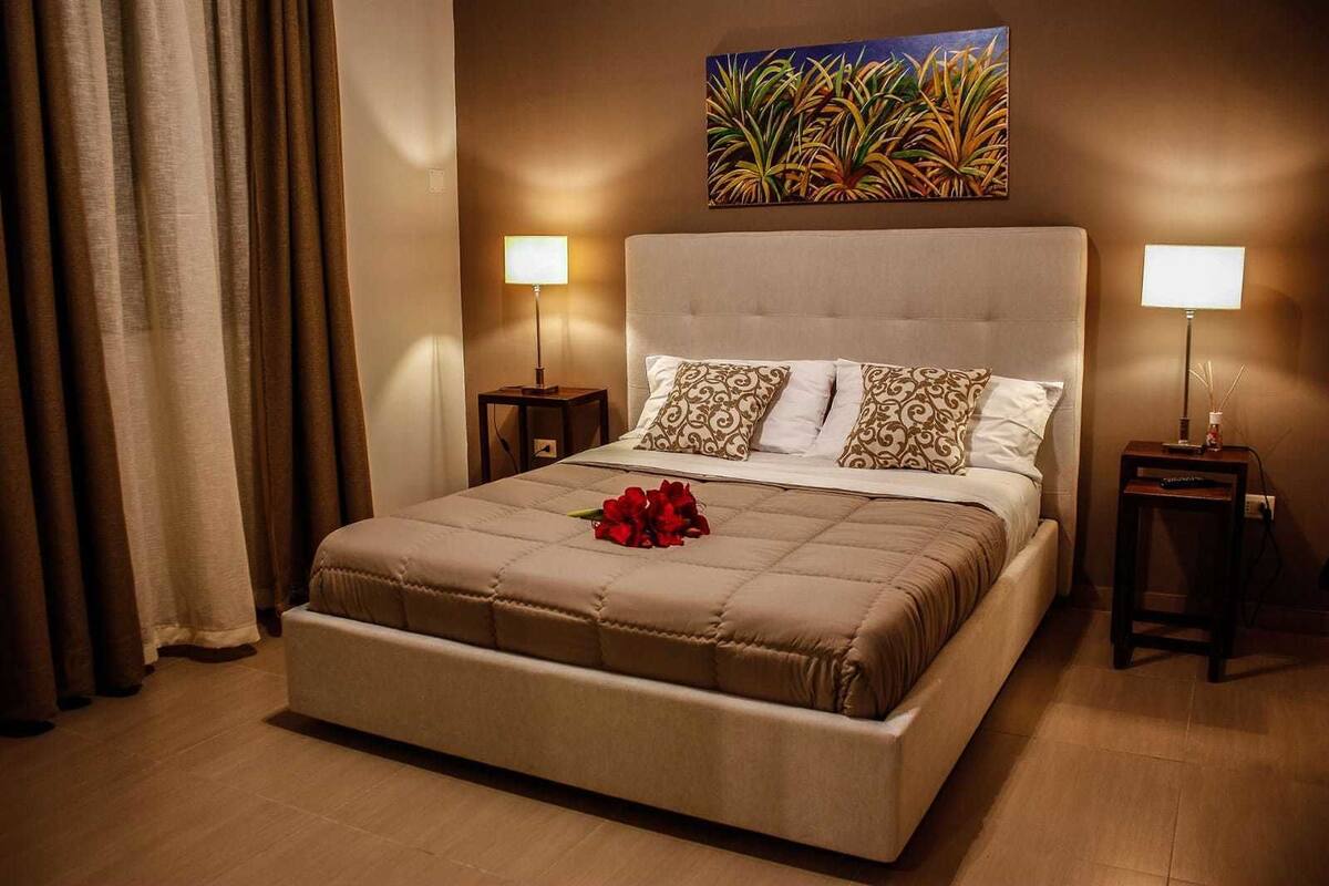 Una habitación de hotel con una cama grande, dos mesitas de noche y un cuadro sobre la cama.