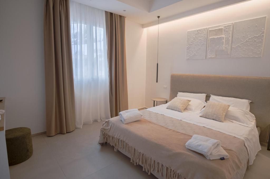 Ein Hotelzimmer mit einem großen Bett, einem Nachttisch, einem Wandbild und einem Fenster mit Vorhängen.
