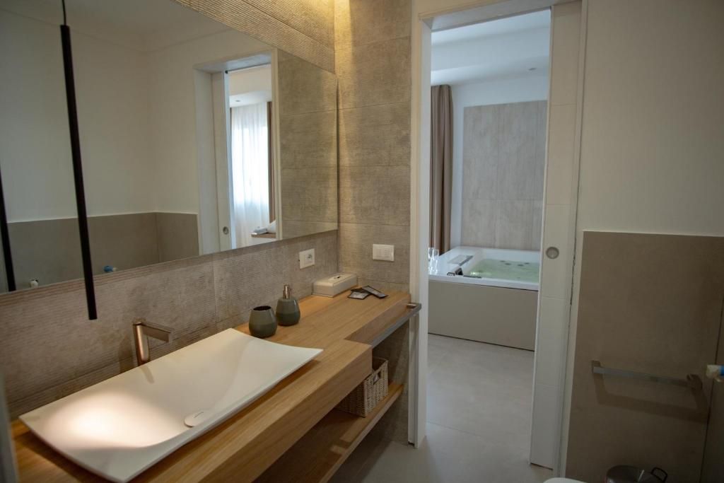 Ein modernes Badezimmer mit großem Spiegel, Holzkosmetikschrank, Badewanne und Duschbereich.