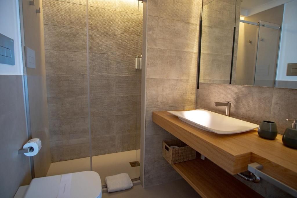 Un baño moderno con ducha, lavamanos y espejo.