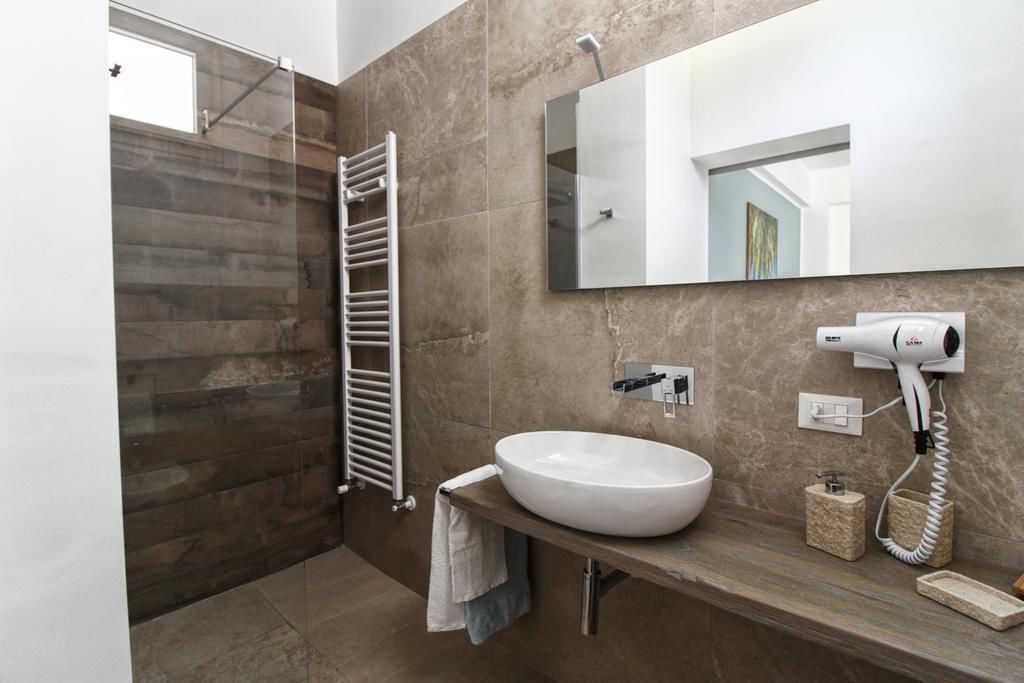 A modern bathroom with a large mirror, a white sink, a towel rack, and a hairdryer.