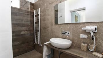 A modern bathroom with a large mirror, a white sink, a towel rack, and a hairdryer.