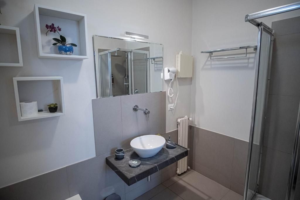 A modern bathroom with a large mirror, a sink, a shower, and a toilet.