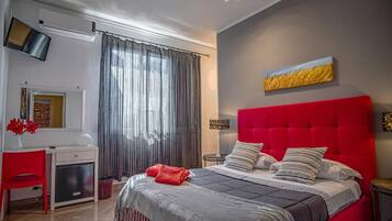 Une chambre d’hôtel moderne avec un lit rouge, un bureau avec une chaise, une télévision et une grande fenêtre avec des rideaux.