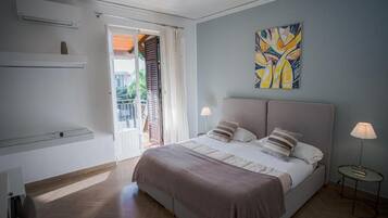 Une chambre à coucher avec un lit, des lampes de chevet, un tableau au mur et une porte coulissante donnant sur un balcon.