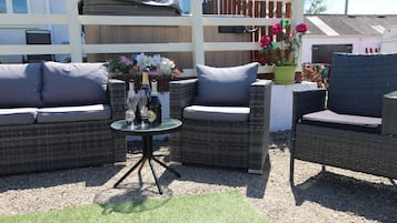 A patio area with wicker furniture, a small round table, and a flower arrangement.