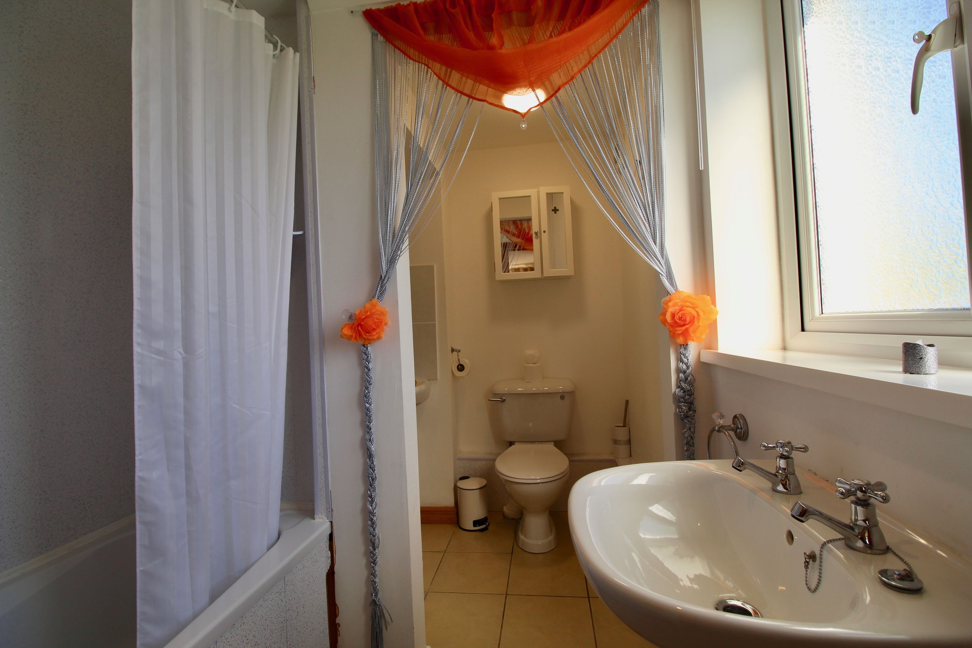 Ein Badezimmer mit weißem Waschbecken, WC und Duschvorhang.