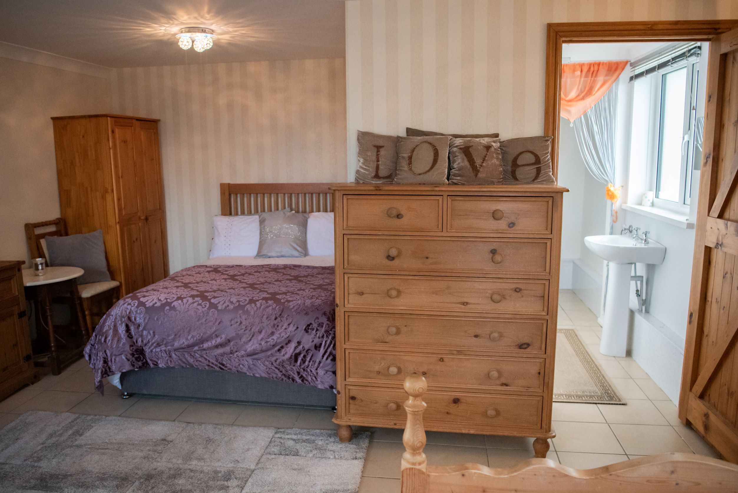 A bedroom with a bed, wooden dresser, and a nightstand.
