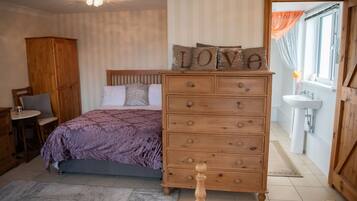 A bedroom with a bed, wooden dresser, and a nightstand.