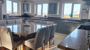 A modern kitchen with a central island, dining area, and large windows. - Bunny Meadows Farmhouse (Carmarthen)