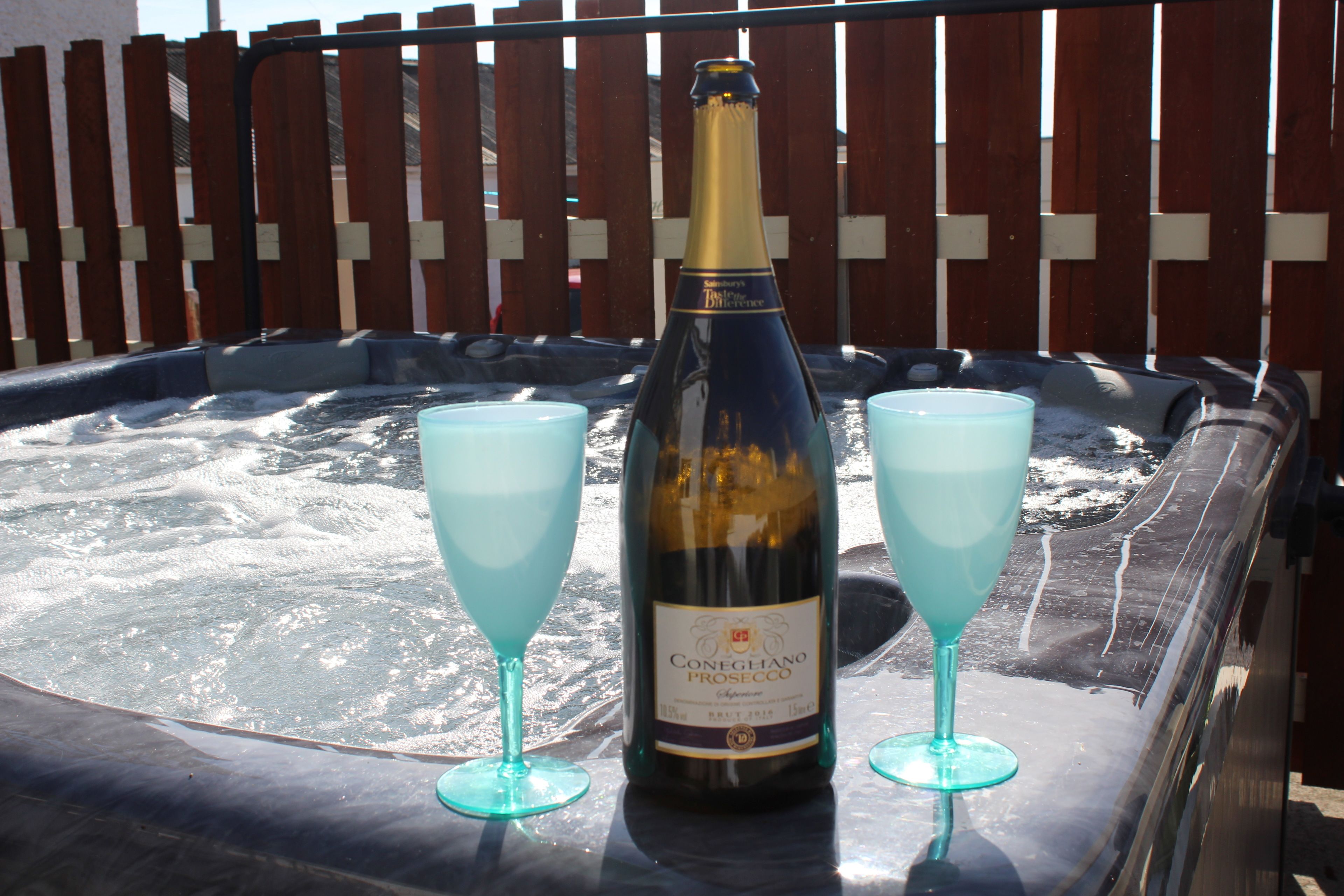 En flaske Conegghiano Prosecco og to glas i en jacuzzi.