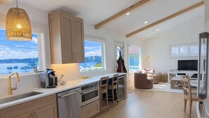 A modern kitchen with a large island, wooden cabinets, and a view of the water. - Front Row Waterfront Views— Steps to Beach, Town & Ferry (Kingston)