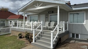 Ein Haus mit überdachter Veranda, weißen Geländern und einer Treppe zum Eingang.