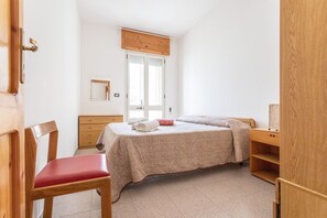 Une chambre à coucher avec un lit, une chaise en bois, une commode et une porte.