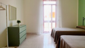A bedroom with a bed, a dresser, a mirror, and a window with sheer curtains. - Villetta Iris (Morciano di Leuca)