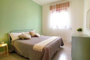 A bedroom with a bed, bedside table, and a window with curtains. - Villetta Iris (Morciano di Leuca)